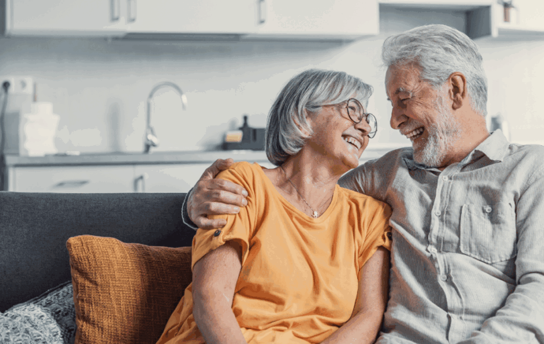 Senior couple on the sofa hugging and smiling at each other