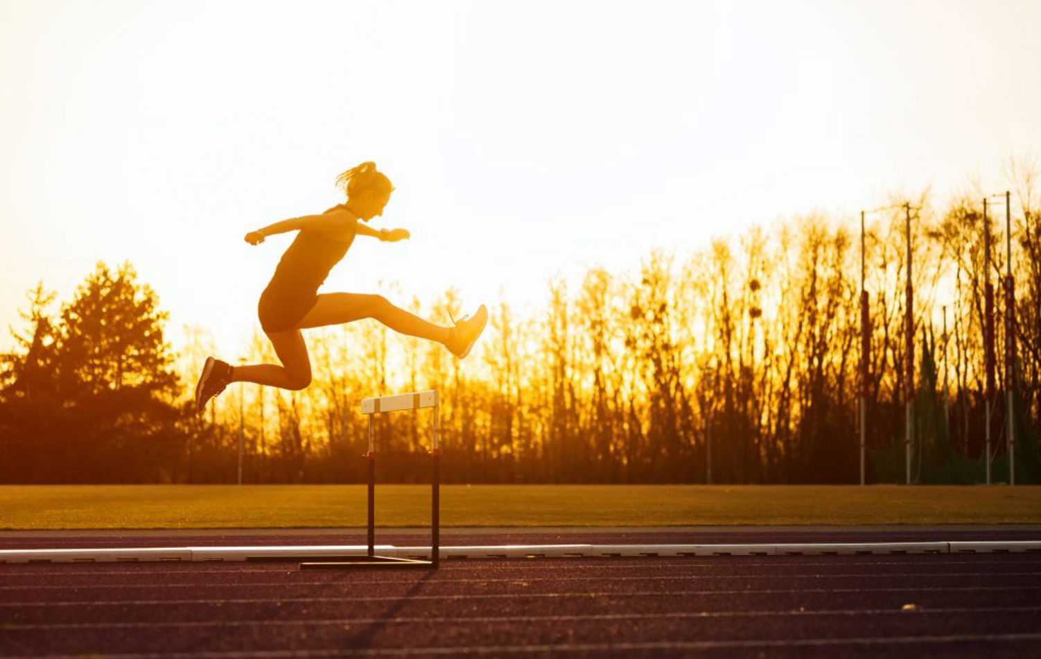 A person jumping over a hurdle on a running track