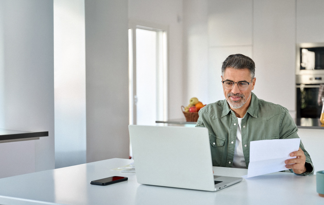 Man alone sat, looking and smiling at his laptop