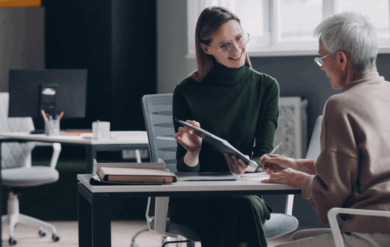 A man having a discussion over an office desk with a business woman