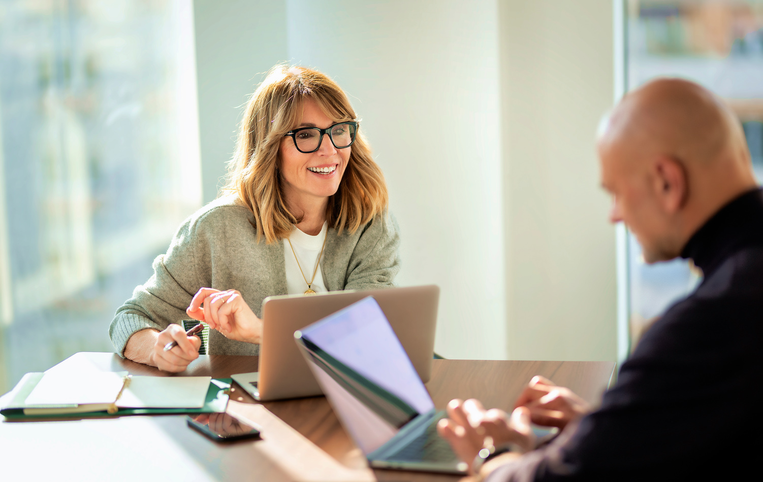 A man and a woman sat in an office discussing finance, accompanied by a blue-purple gradient circle in the middle