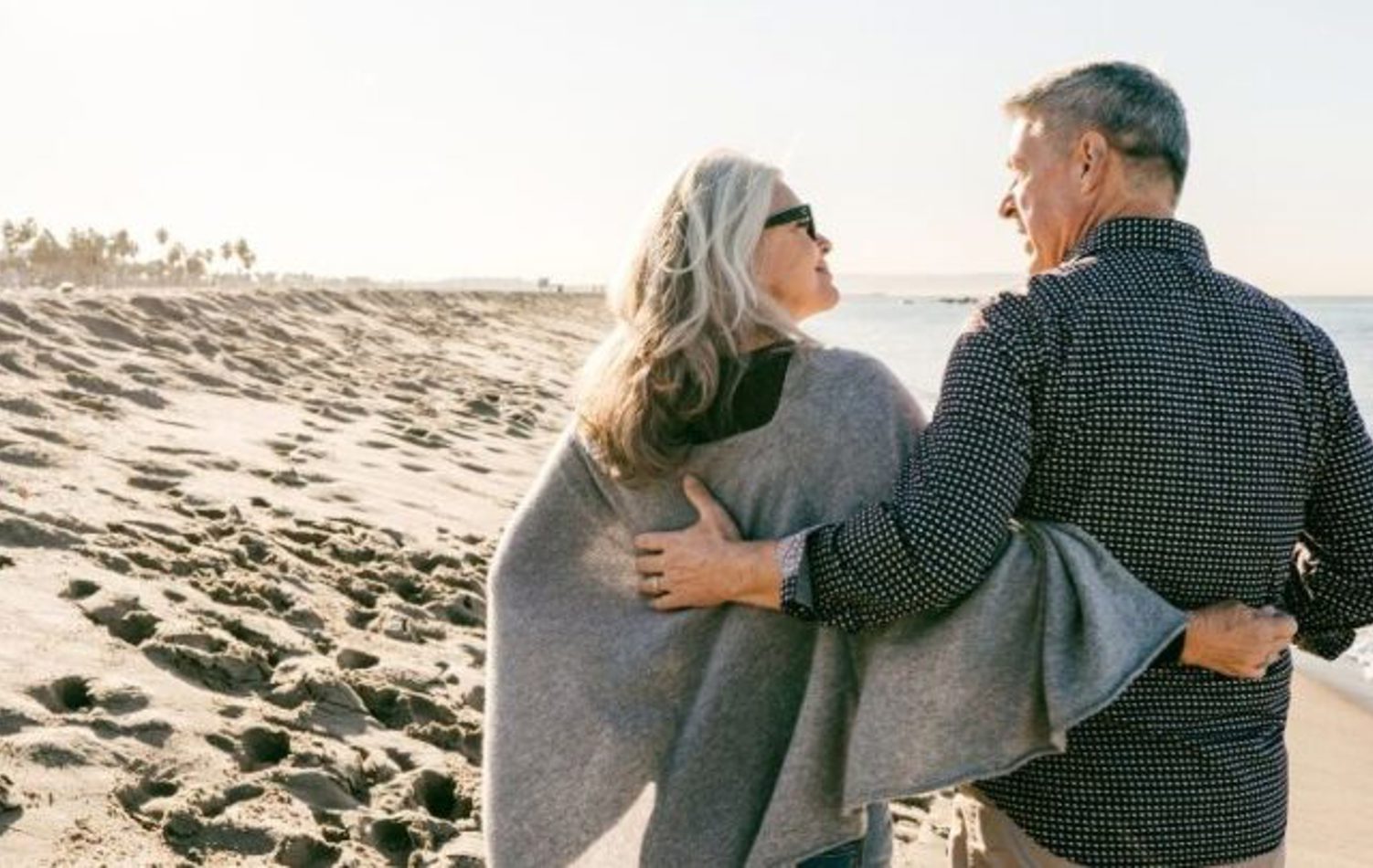 A senior couple holding hands as they walk on the beach