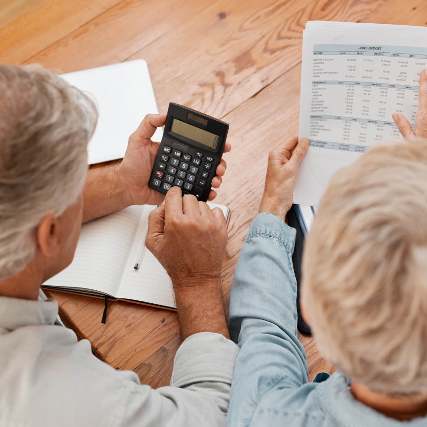 A man and a woman sat looking at their finances with a calculator and note pad